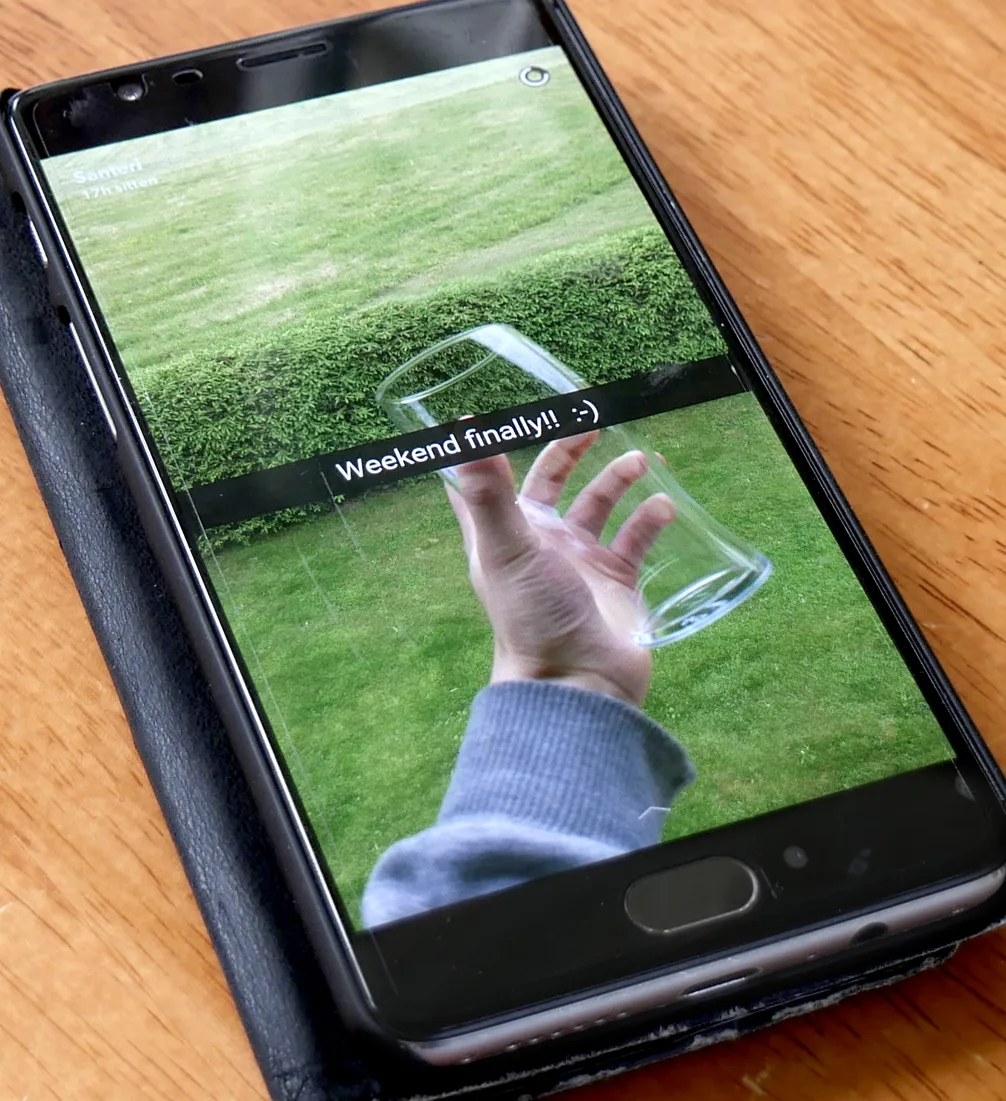 A snap open on a phone, a hand holding a glass over a lawn with the caption Weekend finally